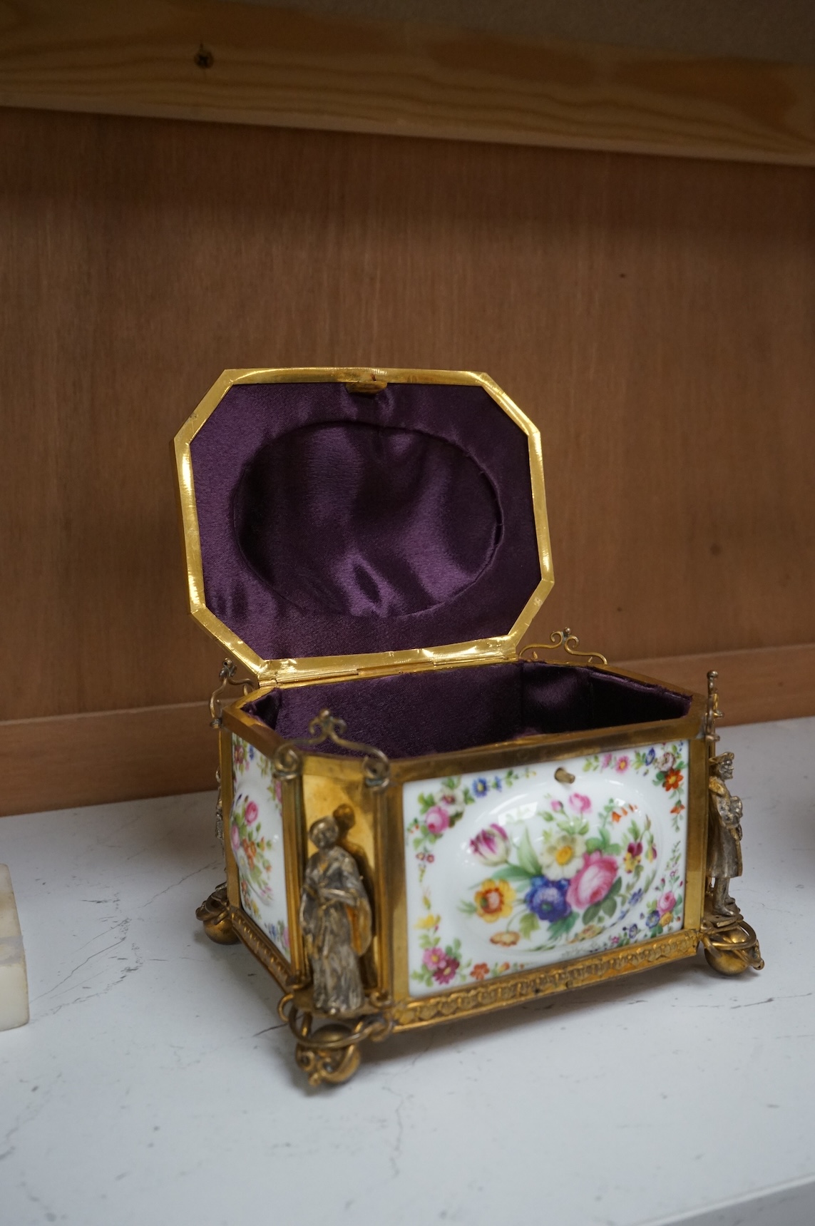A gilt-brass figural and floral porcelain jewellery casket, 14cm wide, 11cm high.